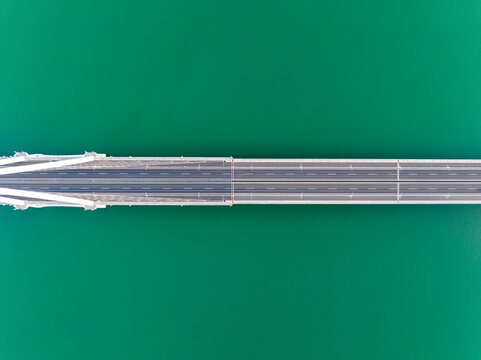 Top Down Aerial View of Bridge Spanning Green Water
