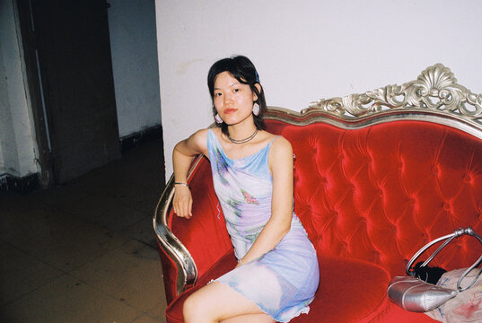 Unbothered &mdash; Reclined Portrait of Young Woman on a Red Sofa