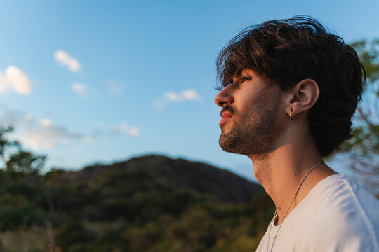 Young man contemplating nature against a warm sunset sky