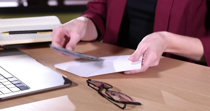 Woman taking money from envelope at wooden table indoors, closeup
