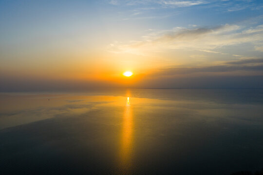 Golden sunset over calm lake with tree silhouettes on shoreline