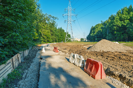 Rural utility corridor under construction with safety barriers and power pylons