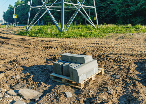 Concrete curbstones on wooden pallet at rural roadside near power pylon