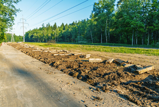 Rural powerline corridor with cleared earth and stacked concrete slabs