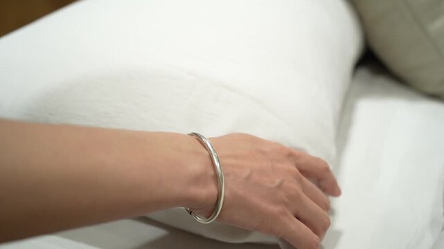 A close-up view of a woman's hand  checking a pillow's softness while browsing through household products in a shopping mall.