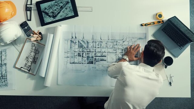 Top view of smart civil engineer drawing and measuring blueprint by using ruler. Aerial view of architect scatch building project plan at meeting table with equipment and safety helmet. Alimentation.