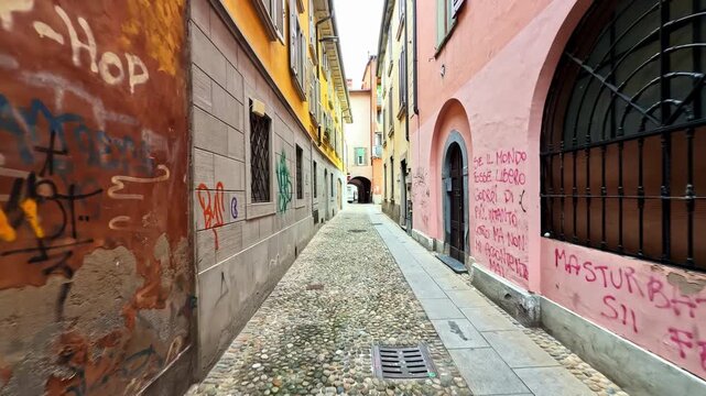 POV Walking Through Narrow Cobblestone Alley Flanked by Colorful Aged Buildings and Graffiti in Bergamo Capturing the Raw Authenticity of Italian Urban Life