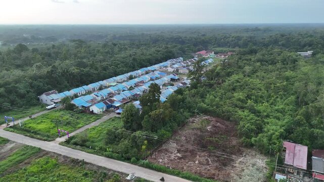 Aerial View of Rural Housing Development With Blue Roofs Nestled Next to Dense Tropical Forest.