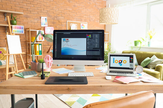 Graphic designer's workplace with computer monitor and laptop in office