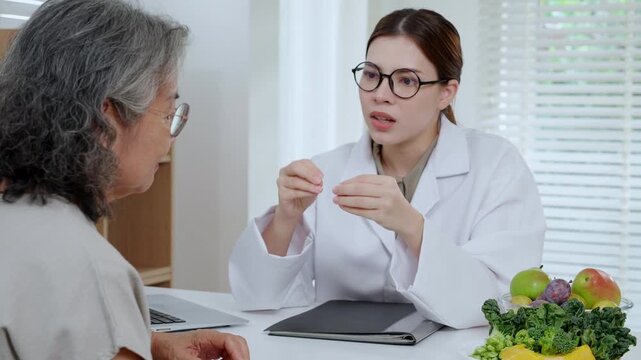 Asian woman nutritionist doctor discussing medical treatment with senior patient, dietitian advice for healthy, wellness and care, nutritionist explaining nutrient control with fruit vegetable.