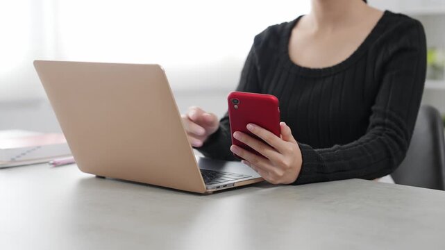 ノートパソコンとスマホを使って作業する女性