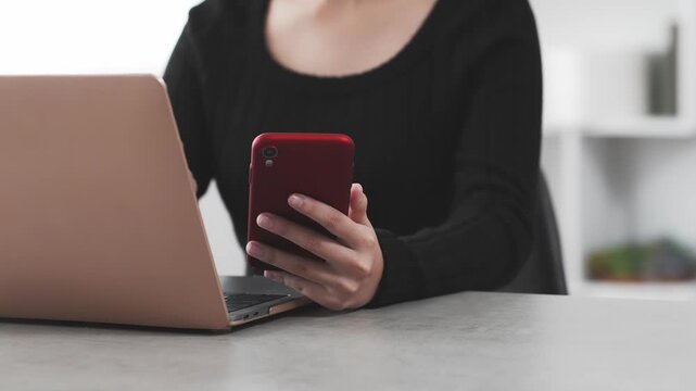 A woman working using a laptop and a smartphone.
