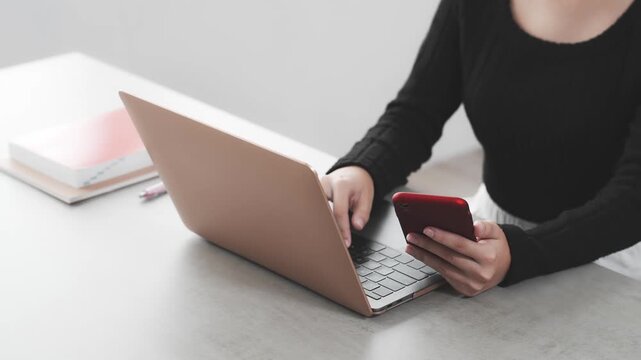 ノートパソコンとスマホを使って作業する女性