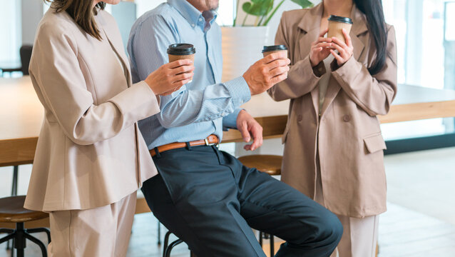 Businessmen and businesswomen chatting while drinking coffee in the office.