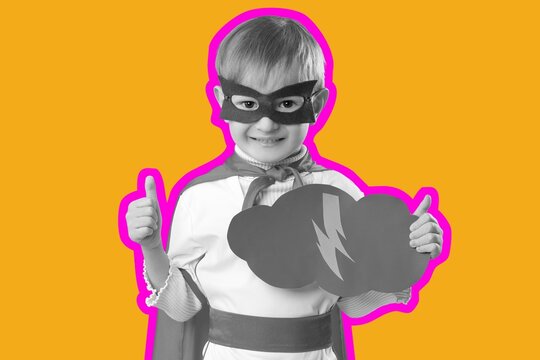 Young boy superhero costume with mask and cape holding lightning cloud icon giving thumbs up on orange background, he gives a thumbs up gesture, power and success