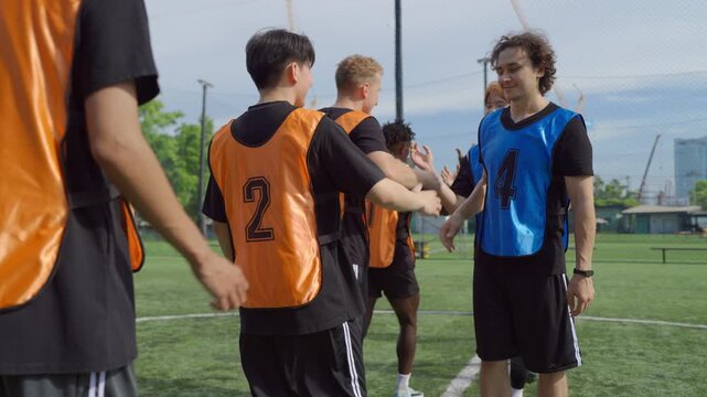 Two teams of diverse football players touching hands before soccer match. 