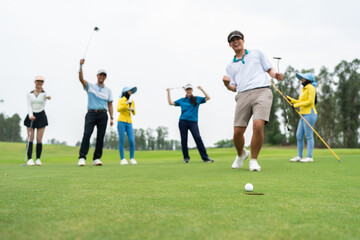 Group of young pro golfers swings their club on scenic golf course. 