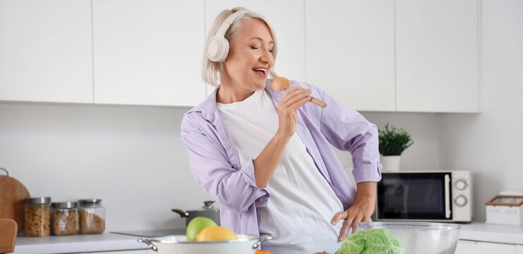 Mature woman with dancing and food o table dancing in kitchen