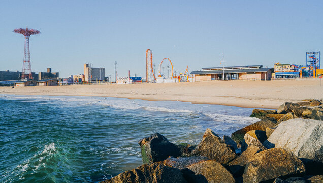 Coney Island panorama in Brighton Beach, New York City, with Atlantic shoreline, amusement rides, and the Parachute Jump tower.
