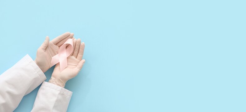 Breast cancer awareness pink ribbon in doctor's hands, medical support and healthcare campaign for women's health