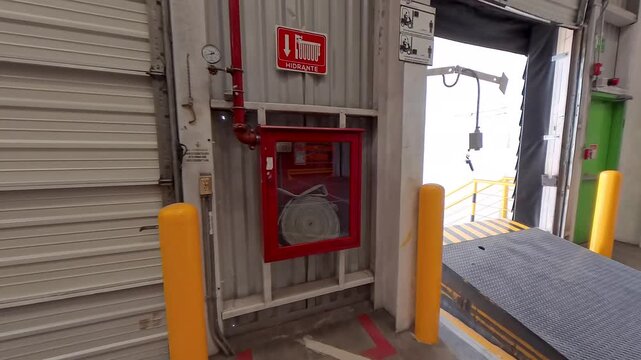 Fire Hose Cabinet Next to Loading Dock in Modern Warehouse. Fire Safety Equipment Installed at Warehouse Loading Dock. Industrial Fire Hose Cabinet Inside Distribution Center. 