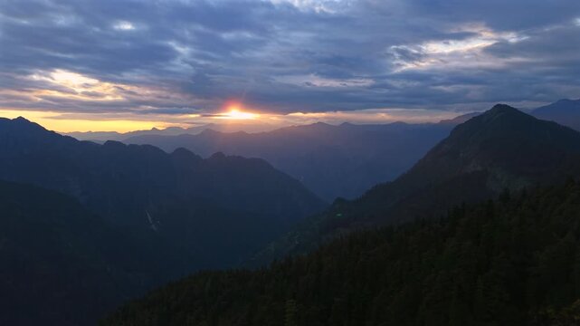 Golden sun rays piercing through clouds above layered Himalayan mountains near Sar Pass Trek in Parvati Valley, Himachal Pradesh, India