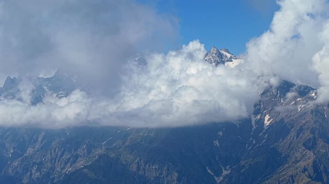 Cinematic aerial of rolling clouds surrounding snow covered Himalayan mountain peaks near Sar Pass Trek and Parvati Valley, Himachal Pradesh, India