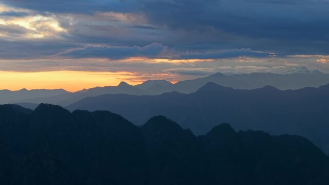 Layered Himalayan mountain silhouettes with dramatic cloud formations and warm sunset light near Parvati Valley in Himachal Pradesh, India.