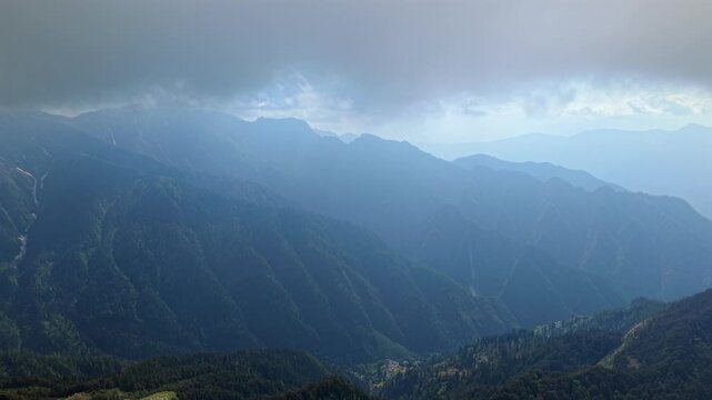 Wide aerial view of layered Himalayan mountain valleys beneath dense clouds near Parvati Valley and Sar Pass Trek India.