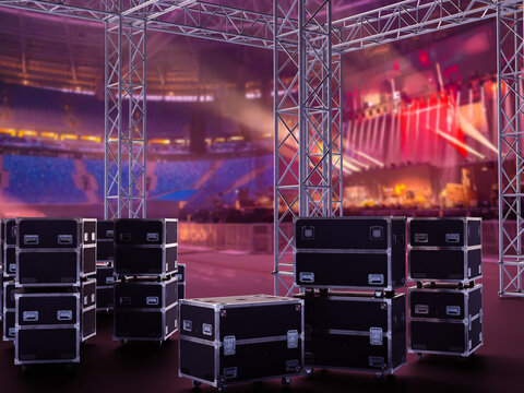 Event staging logistics. Equipment cases stand under truss structures before concert stage setup in large arena.