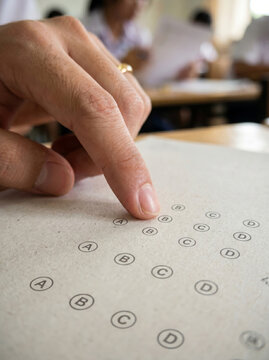 Hand filling out standard optical mark recognition bubble answer sheet