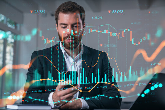 Smiling businessman talking holding using smartphone typing at office workplace with notebook. Concept of distant work, business education. Forex market stock and charts, graphs.