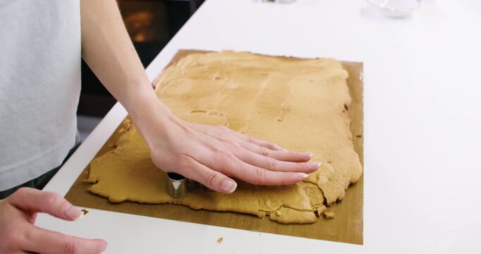 Bakery process. Cookie making. Confectioner hand cut traditional gingerbread man treat from dough sheet. Sweet festive meal recipe.