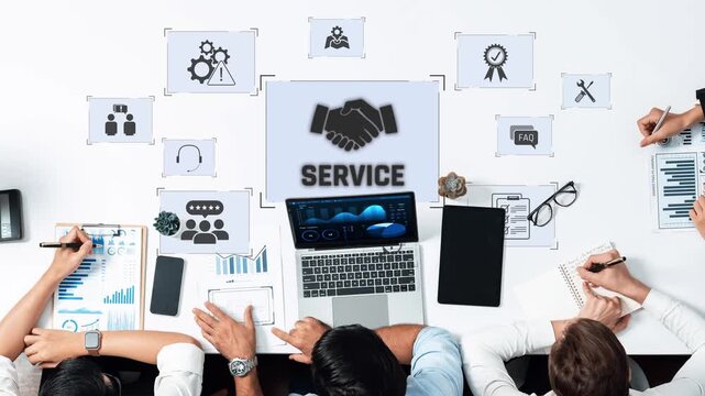 A focused team engages in strategic discussions about service enhancement, utilizing digital tools and data visuals on a modern work desk, fostering collaboration and innovation. Raster
