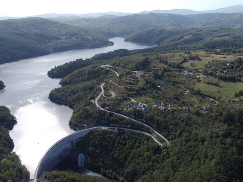 Aerial view of dam and reservoir surrounded by green forest hills in Serbia near Uzice. g.