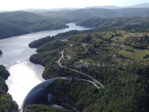 Aerial view of dam and reservoir surrounded by green forest hills in Serbia near Uzice. g.