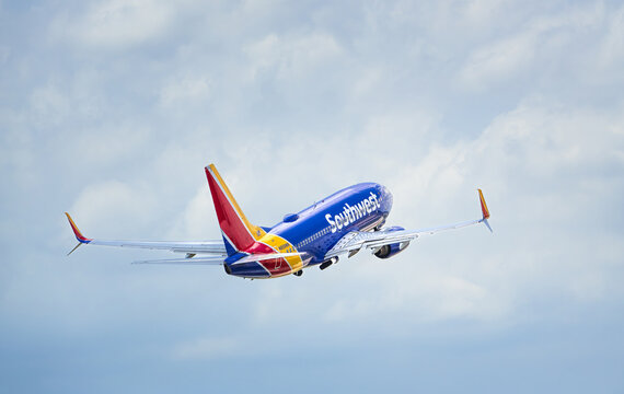 Southwest Airlines aircraft, Boeing 737, airborne over Dallas Love Field Airport (DAL), blue skies and white clouds.
