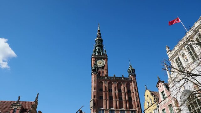 The town hall clock tower and a Gdansk flag waving in slow motion. Poland.