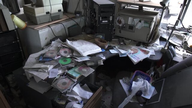 Slow zoom on a messy desk with papers and CDs in an abandoned Fukushima office.