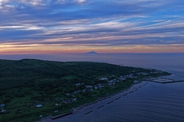 Obraz premium Aerial drone photo of coastal village and distant mountain at dusk, Teuri Island, Hokkaido, Japan