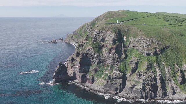 Aerial drone footage of rugged sea cliffs and lighthouse on Hokkaido coast, Japan