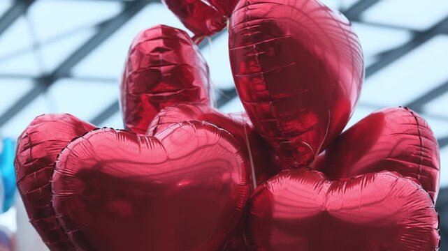 Red Heart-Shaped Balloons Tied To Strings Flying In The Shopping Mall