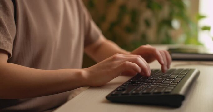 Woman's hands typing on black computer keyboard, close up shot capturing dynamic motion.