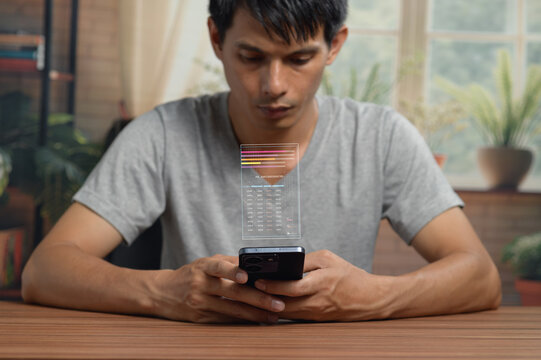 Young man using smartphone to analyze data chart at home workspace