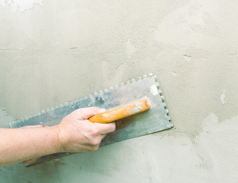 Hand smooths fresh plaster with a trowel