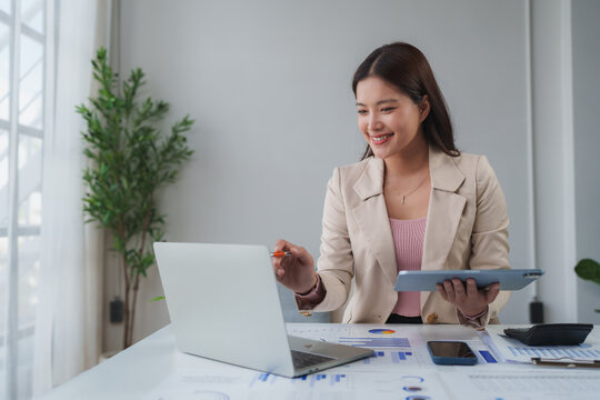 Professional woman analyzing business data using laptop and tablet