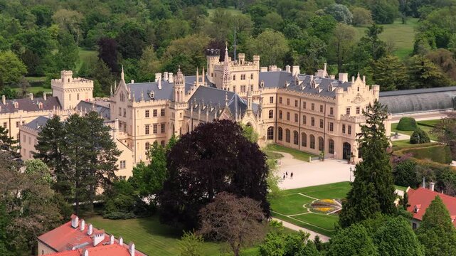 Aerial drone view of Lednice Castle, a grand Neo-Gothic palace surrounded by lush parkland and formal gardens, Moravia, Czech Republic.