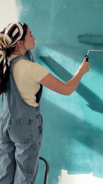 Woman, back and painting wall with brush for creativity, therapeutic hobby and interior design. Process, artist and home decor with diy project, maintenance and paint for renovation and inspiration