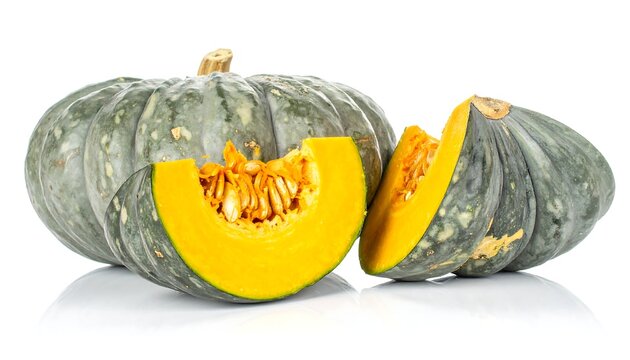 Green pumpkin and cut slices displaying the orange flesh and seeds on a white background