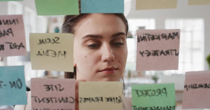Business, woman and planning with sticky notes in office for task priority, workflow or schedule. Female person, glass or brainstorming with ideas, reminder or agenda for project or work delegation